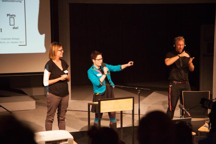 Präsentation Projekt "Platz Da!" mit Stefanie Wiens und Charlotte Röttger Zwei Teammitglieder des Projektes Platz Da! und ein DGS-Dolmetscher auf der Bühne