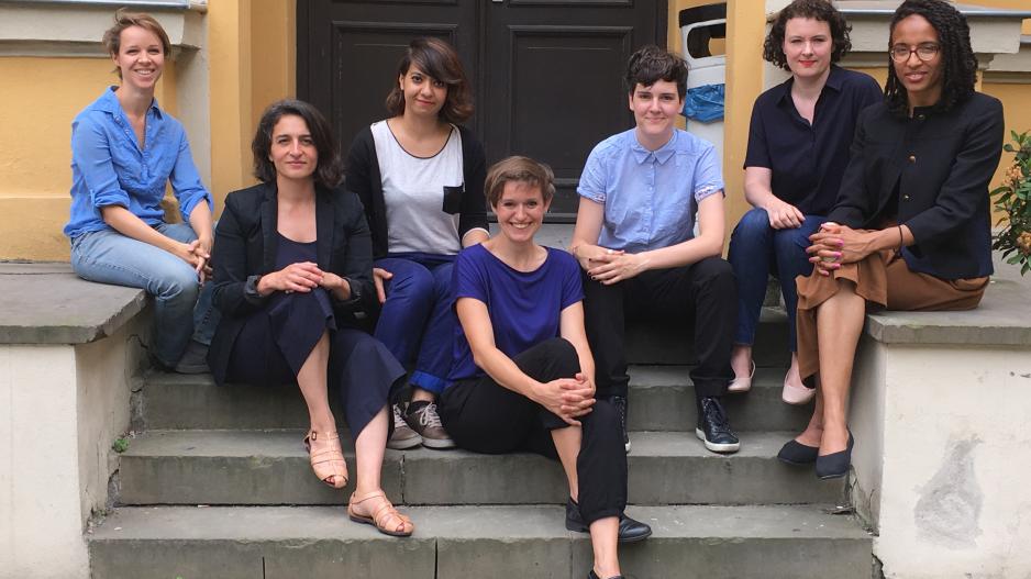 Team Diversity Arts Culture Die sieben Teammitglieder sitzen auf einer Treppe und schauen in die Kamera